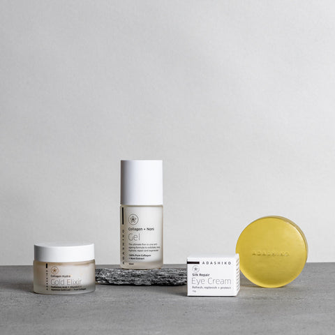 Adashiko Collagen and Noni Gel, Silk Repair Eye Cream, mask and cleansing bar arranged on a neutral stone surface