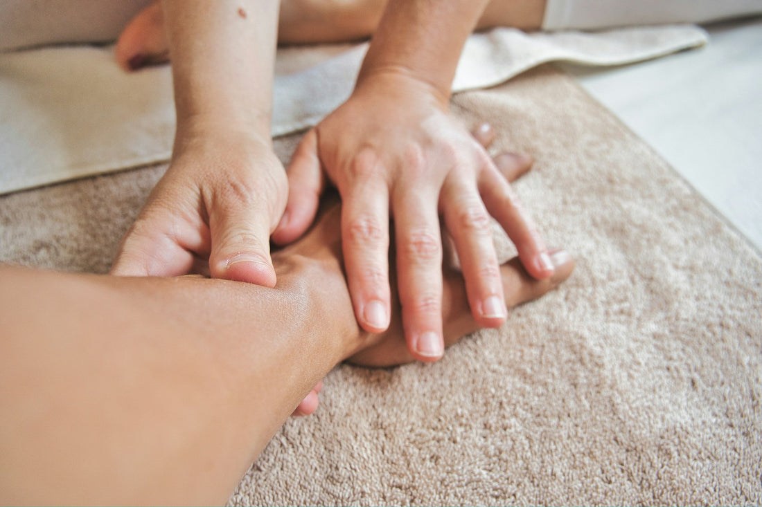A pair of hands receiving a hand massage on a soft towel