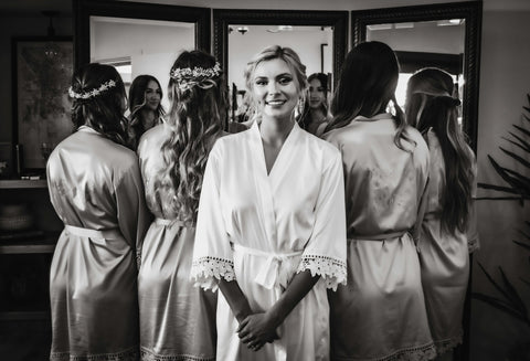 A bride in a robe with her bridesmaids getting ready before the wedding
