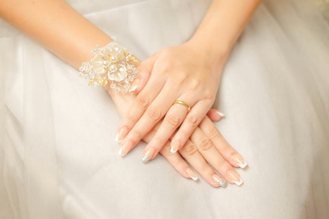 A bride's hands with a wedding ring and a soft neutral manicure